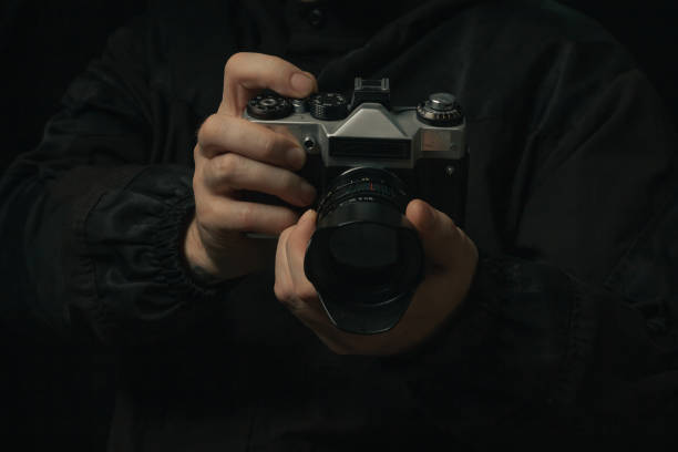 istock man holding Retro film photo camera isolated on black background soviet 1441336578