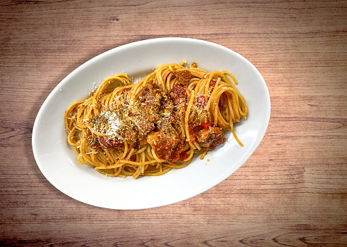Oval plate of spaghetti all'amatriciana, on the wooden table. Italian food specialty.