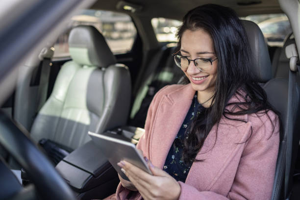 brunette woman browsing on a tablet - auto mobile imagens e fotografias de stock