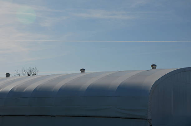 istock container building permanently forms a warehouse with offices. covered with a rubber sheet on tent structure. ventilation with help of a stainless steel propeller chimney. round, hangar, blue sky 1441345532