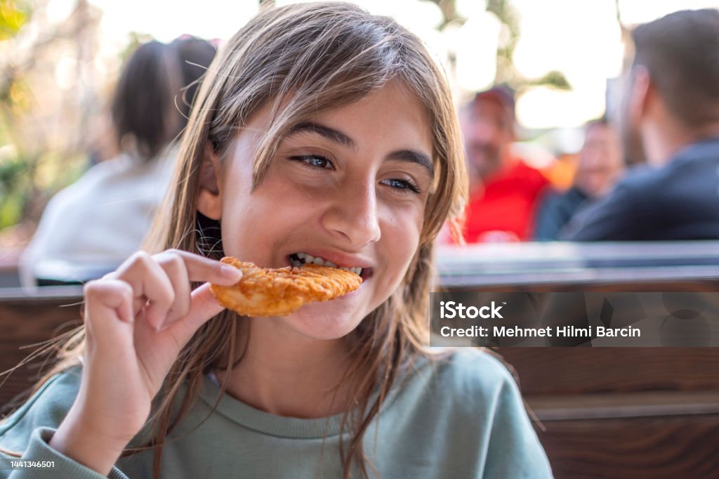 Beautiful little girl enjoying fried chicken Cute Turkish girl eating fried chicken Biting Stock Photo
