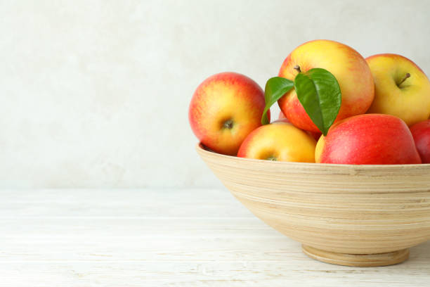 istock Bowl with red apples on white wooden table 1441347111
