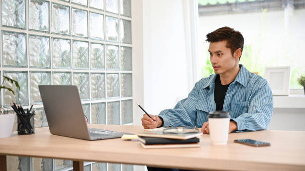 istock Handsome Asian male freelancer remote working in coffee shop, using laptop 1441347122