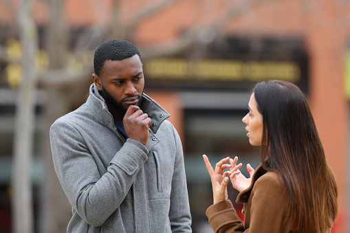 Suspicious man listening a woman talking in winter