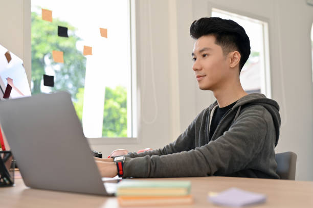istock Handsome Asian male programmer or web developer in casual clothes working at his desk. 1441350291