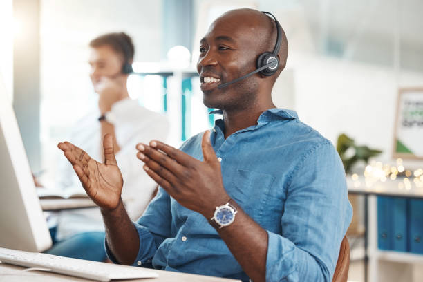 call center, telemarketing and customer service with a business man working in an office and consulting on a headset. help, crm and contact us with a black male consult at work on a computer - touching imagens e fotografias de stock