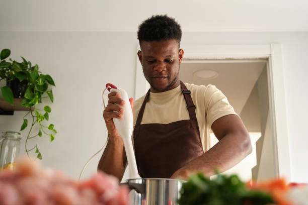 istock Young african man using a blender to prepare chicken mince. 1441353324