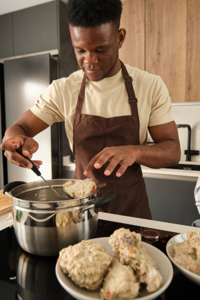 istock Young african man preparing boiled chicken mince with vegetables recipe. 1441353901