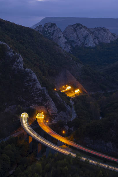 istock Car lights on the highway between mountains 1441353936