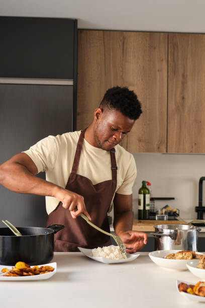 istock Young african man serving rice on a plate. 1441354027