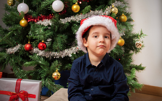 Frustrated child on christmas holiday looks at you sitting on a floor at home in the night