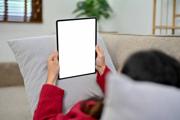 istock Asian woman relaxing in her living room, watching something on her tablet while lying on sofa 1441354784