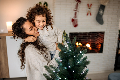 Mother and daughter decorating christmas tree together