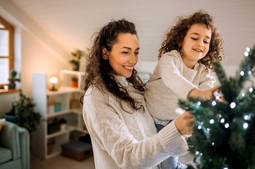 Mother and daughter decorating christmas tree together