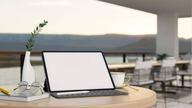 istock Tablet mockup on table over blurred background of modern outdoor restaurant seating space 1441356176