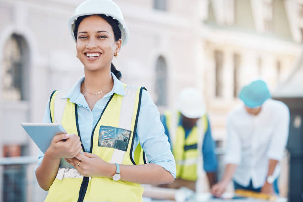 istock Construction, tablet and architecture with a woman builder or architect working on a building site in the city. Engineer, design and technology with a female designer and her team in the background 1441358274