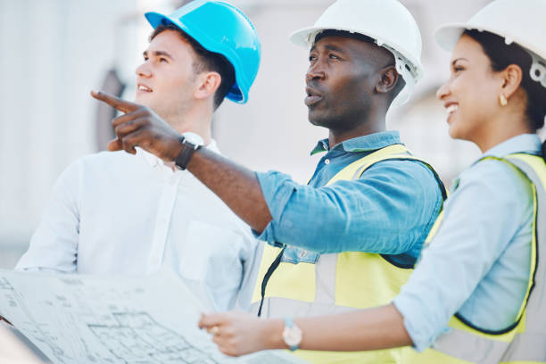 istock Architect at construction site, discussion on blueprint or plan for building with staff. Team of employees of architecture company, with helmet working on strategy for real estate project or property 1441358280