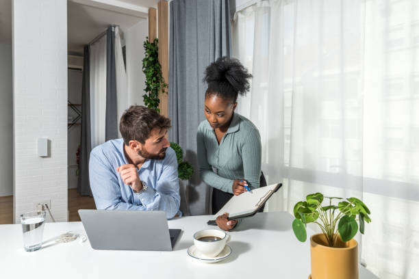 zwei geschäftspartner arbeiten im büro, schauen und lesen statistiken am ende des kalenderjahres auf dem laptop. geschäftsleute kleine firmeninhaber, die computer für den online-handel verwenden. - the end report finishing document stock-fotos und bilder