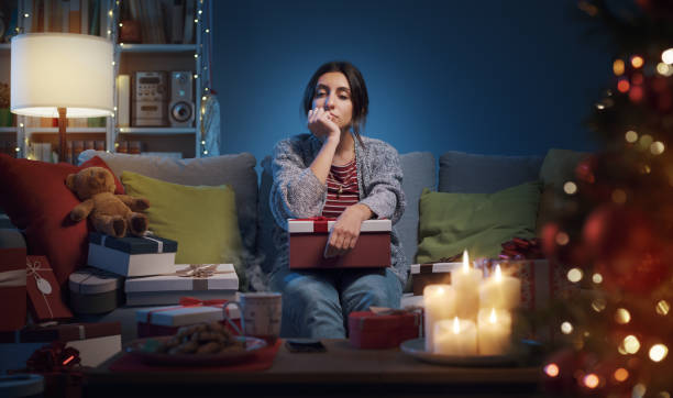Disappointed woman opening Christmas gifts stock photo