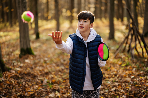Autumn outdoor portrait of boy play with catch and toss ball game.