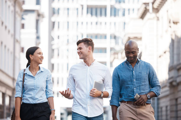istock Business people, friends and city group walking, talking and chatting about work project while outside on an urban street. Diversity, happy and employees planning, traveling and social on commute 1441360540