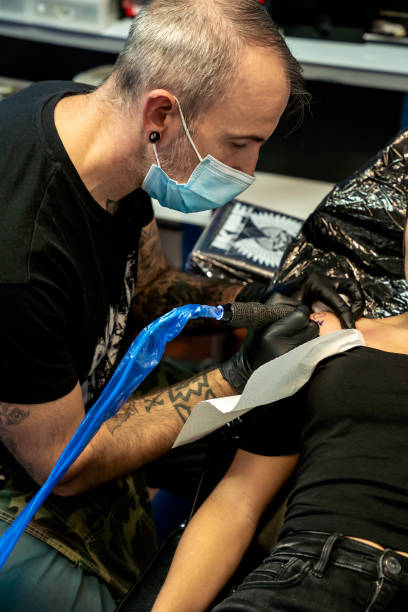 istock Tattooist concentrating while working on a tattoo - concept of work and concentration 1441361562