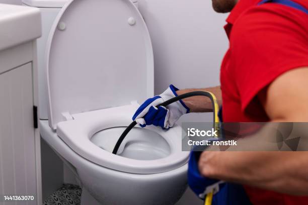 Plumber Unclogging Blocked Toilet With Hydro Jetting At Home Bathroom Sewer Cleaning Service Stock Photo - Download Image Now
