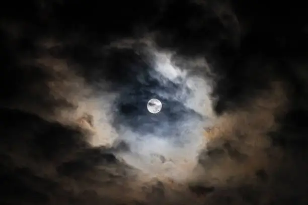 Photo of Full Moon in the night sky with dramatic clouds