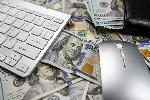 beautiful white computer keyboard on which a large sum of dollars is laid out close by limply isolated. internet income Quick money