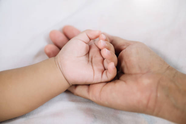 istock Close up baby hand on mother's hands  in sun light 1441365792