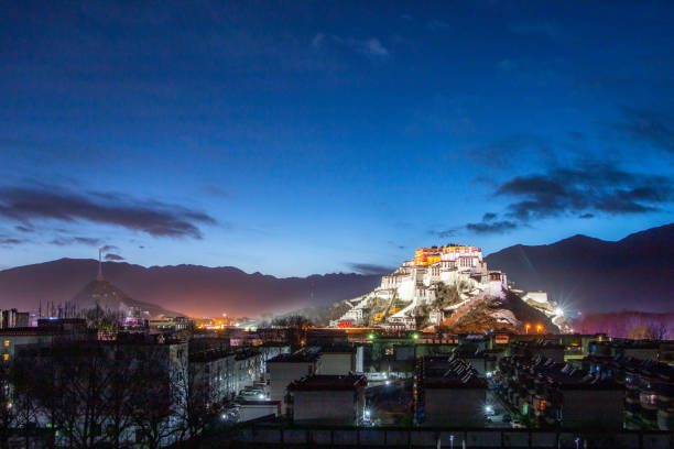 Close-up view of the ornate architecture of Tashi Lhunpo Monastery in Shigatse, Tibet, featuring red, white, and black walls, golden ornaments, and traditional Tibetan decorative patterns under clear sky.