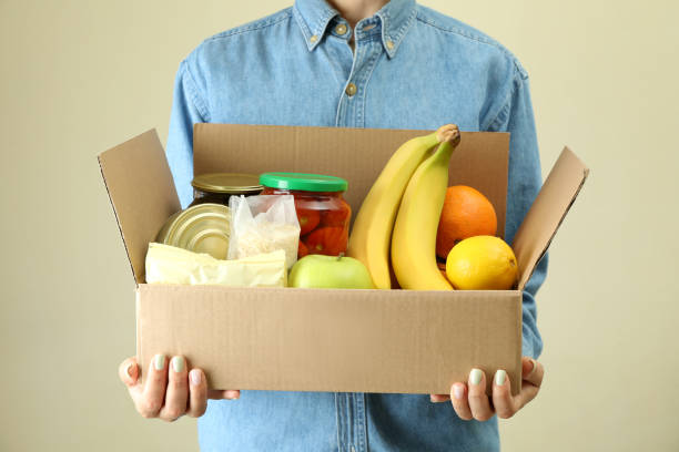 istock Woman holds donation box on beige background 1441367579