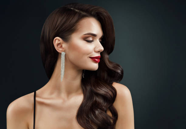 istock Beauty Model Face Profile with Red Full Lips Make up. Beautiful Woman Side view Curly Waves Hairstyle and Silver Earring over dark Background. Women Holiday Makeup 1441368717