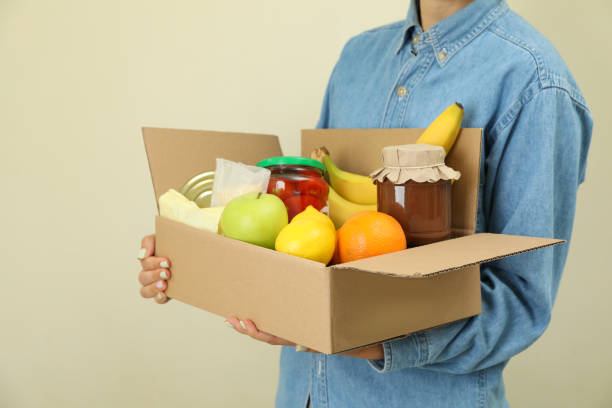 istock Woman holds donation box on beige background 1441368736