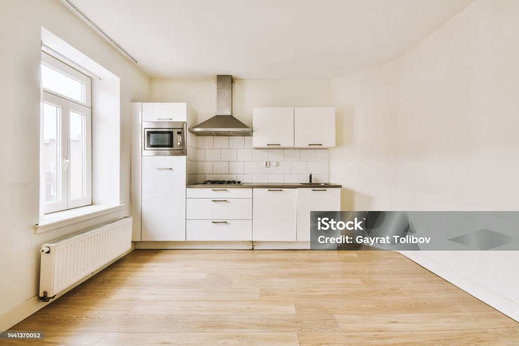 View of a spacious bright room with a small open kitchen View of a spacious bright room with a small open kitchen against the wall in a minimalist style Kitchen Stock Photo
