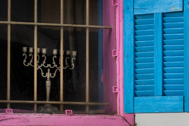 Silver Hanukkah menorah in window behind metal bars