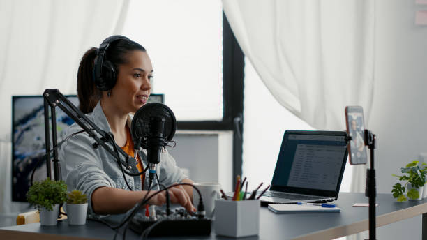 istock Internet live talk show host broadcasting with smartphone while tweaking sound on mixer 1441374511