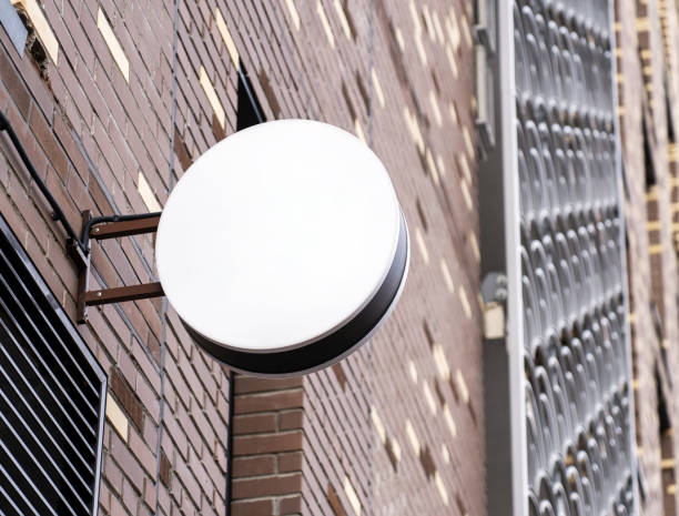istock Blank white round store signboard mockup. Empty circular illuminated shop lightbox template mounted on wall. Mock up of illuminated blank signboard. Place for text, outdoor advertising, banner 1441374639