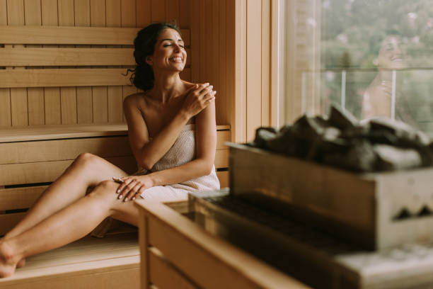 jeune femme détendant dans le sauna - sauna health spa healthy lifestyle wellbeing photos et images de collection