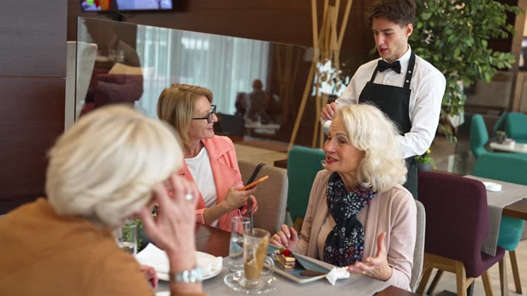 Senior woman making a contactless payment at a restaurant using her cell phone