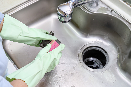Women cleaning the kitchen sink with sponge