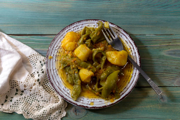 Stewed, green beans and potatoes with vegetables and sauce on a wooden table close-up