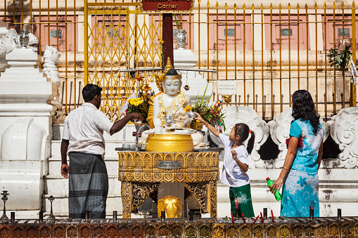 Yangon, Myanmar - January 3, 2014: Myanmar family worshipping Buddha in in Shwedagon Paya pagoda - the most sacred Buddhist pagoda in Myanmar