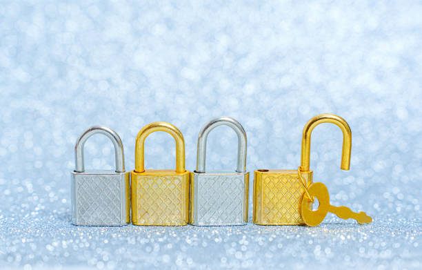 Four shiny metal keyed padlocks arranged in a row on a sparkling background. One padlock is open.