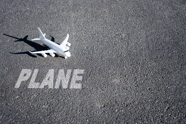 Model aircraft and word PLANE painted on the runway with copy space