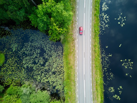 Drone, aerial view on a road that goes along the side of the lake in Halmstad, Sweden. Plenty copy space, no people. Lake surrounded by forest and trees. No people in the image. Idyllic scenery of southern Sweden. Summertime image.