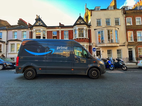 London, UK - 11 November, 2022: color image depicting an electric Amazon Prime delivery van making a delivery on a street in central London, UK.