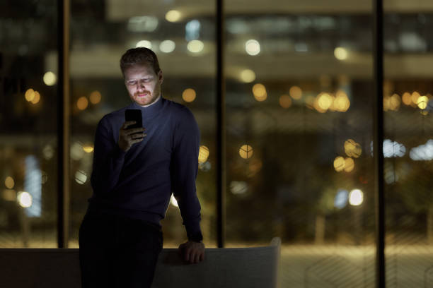 istock Redhead man text messaging on cell phone indoors at night. 1441388448