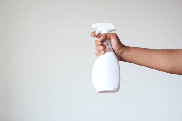 istock holding a white color disinfectant spray bottle against white wall 1441389309