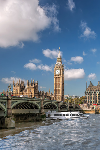 Famous Big Ben with bridge over Thames and tourboat on the river in London, England, UK